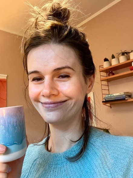 Katja outdoors, holding a coffee